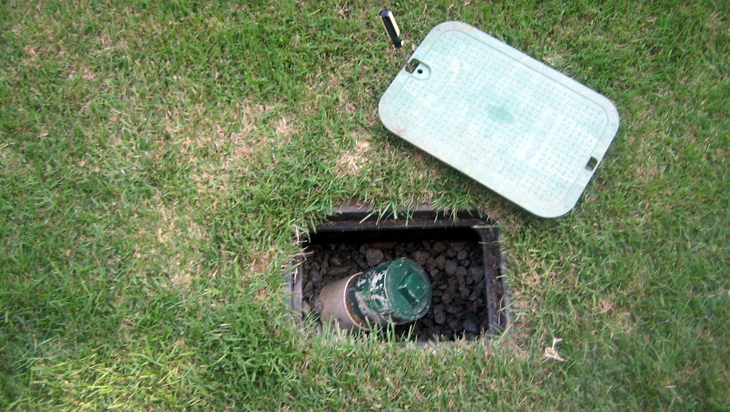 Sewer cleanout with box lid open, showing gravel