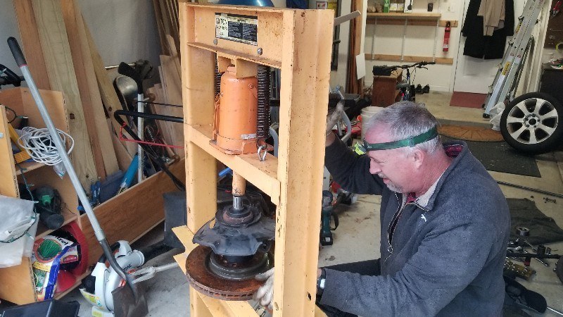 Mobile mechanic with his portable press fixing bad wheel bearings in my garage at home
